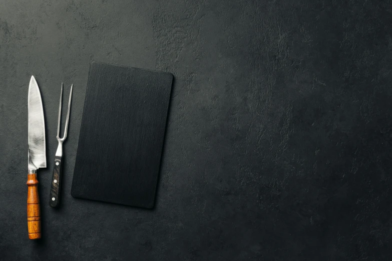 a knife and a napkin on a dark surface