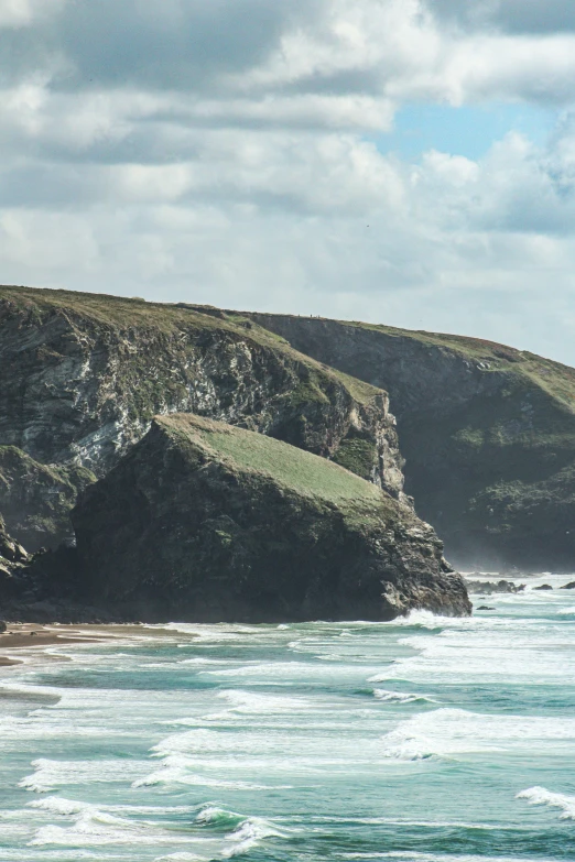 the water is blue and calm and there is a sheep on the cliff