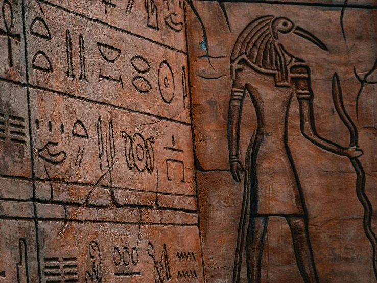 an egyptian wall with an ancient man writing