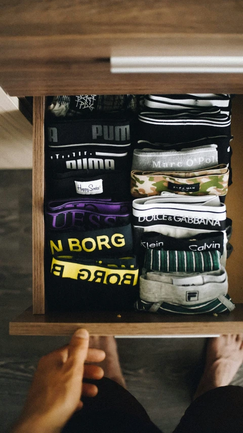 a person is looking inside an open drawer filled with clothes