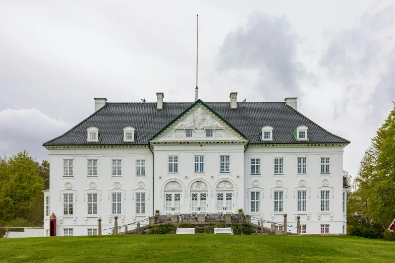 the front of an elegant white building with green grass