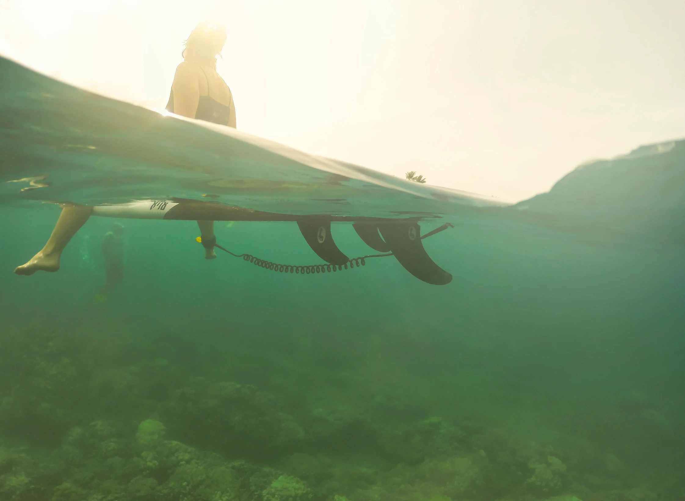 a man under the surface of the ocean near his surfboard