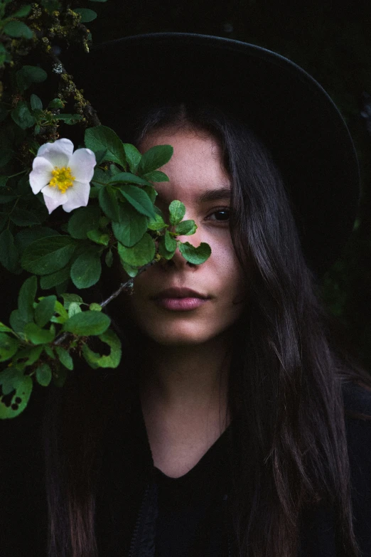 a woman is looking through some foliage