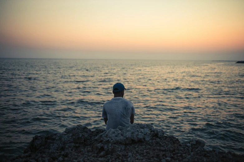 man sitting on the beach looking out at the ocean