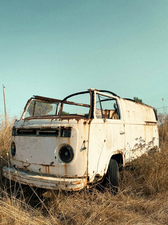 a broken and rusted out truck in a field