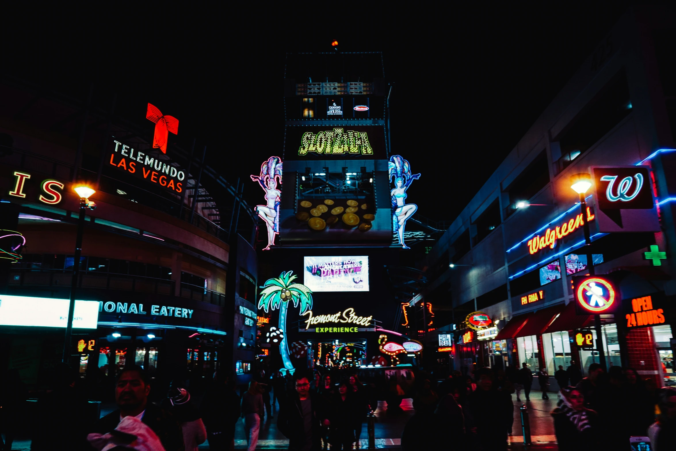 a city street at night with people walking down the street