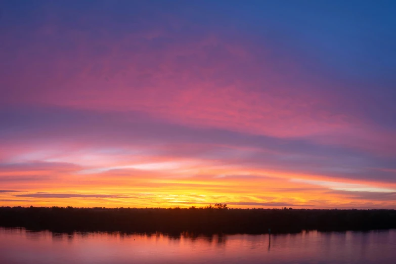 a lake with several boats sitting on the shoreline at sunset