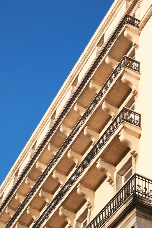 an apartment building with black balconies against a clear blue sky