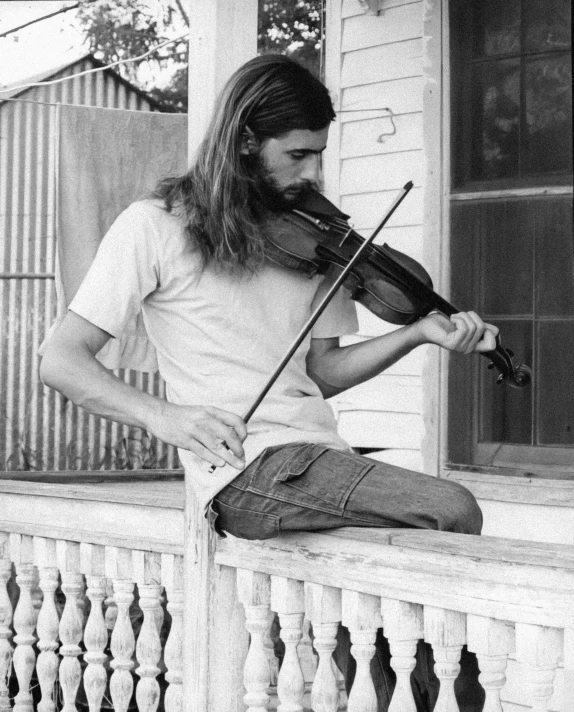 an old po of a man sitting outside playing the violin