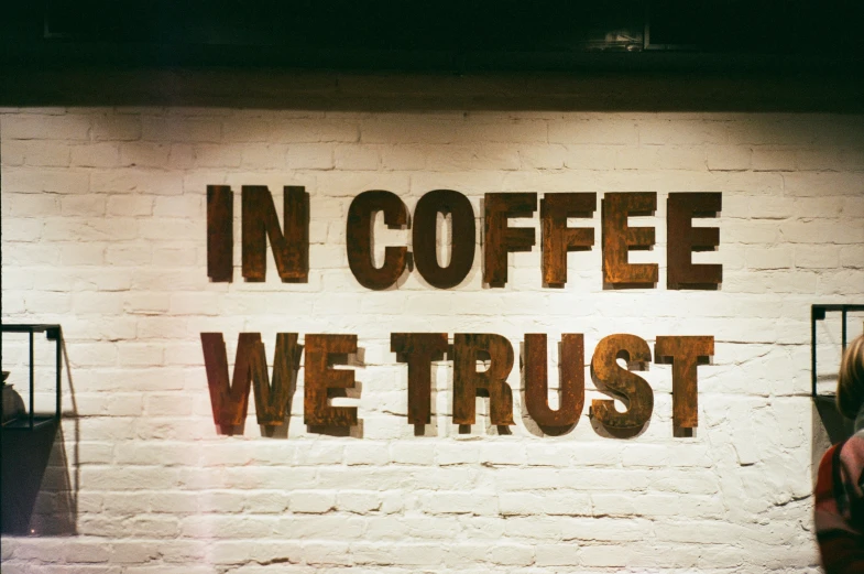 a brick wall with words that read in coffee we trust