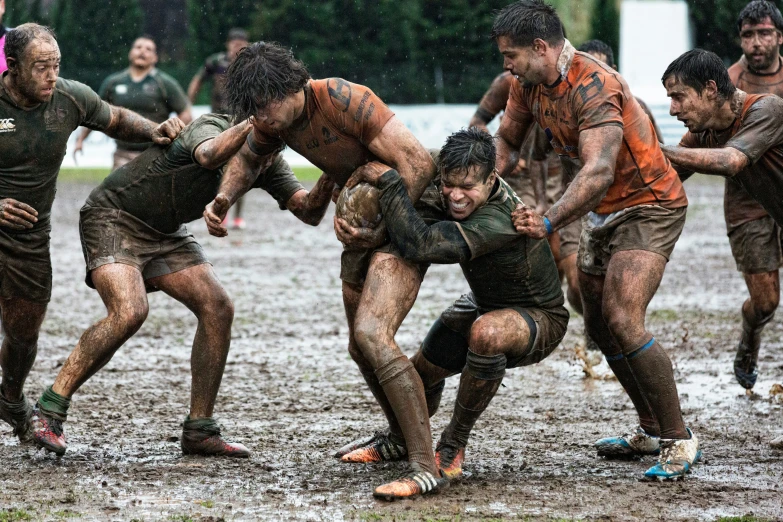 several men playing in a muddy mud - covered field