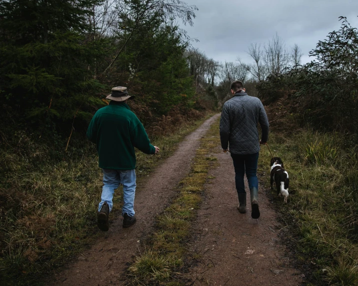 two people walking down a path with a dog