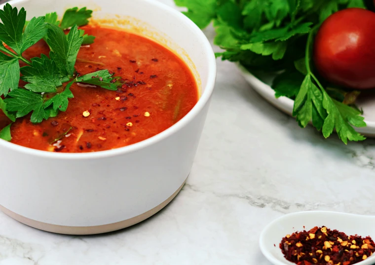 two bowls of tomato soup with parsley on the rim