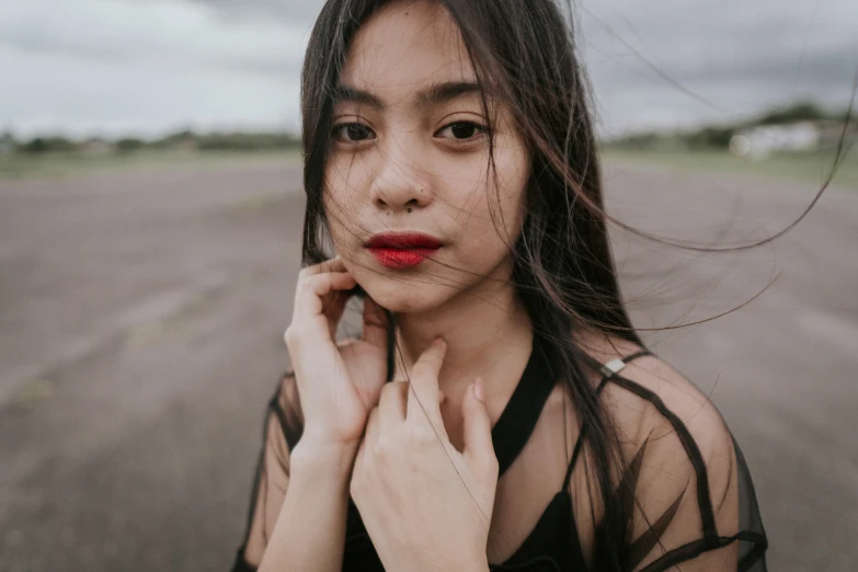 woman with red lipstick standing by road in open area