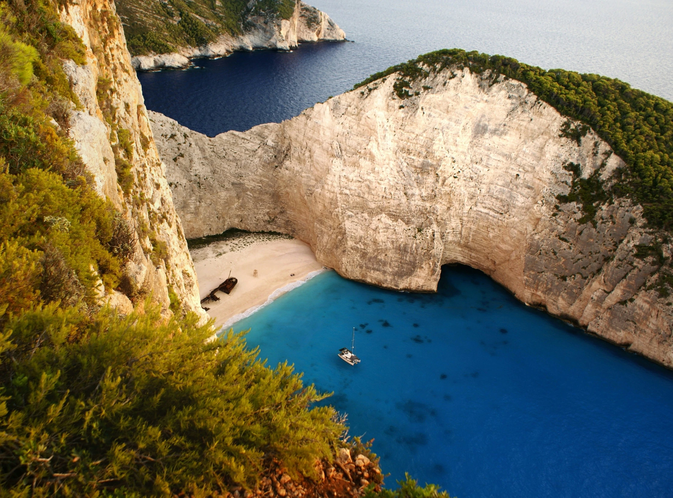 boat sitting in blue ocean beside large white rock arch