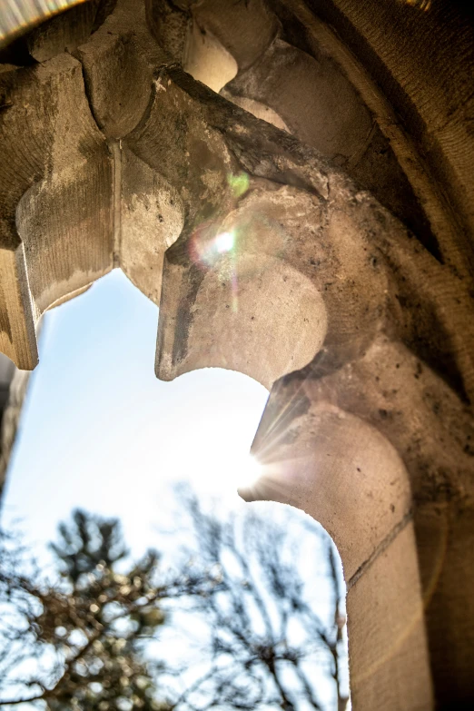 sun shines through the arch of an old building