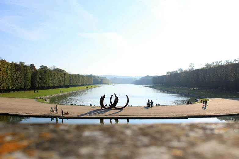 people standing on the edge of a pond with some water