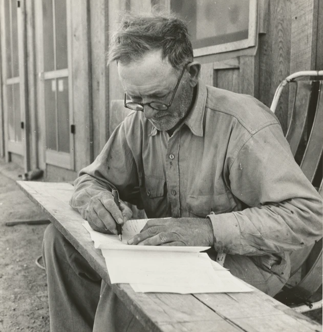 a man with a pen sitting at a table writing in a book
