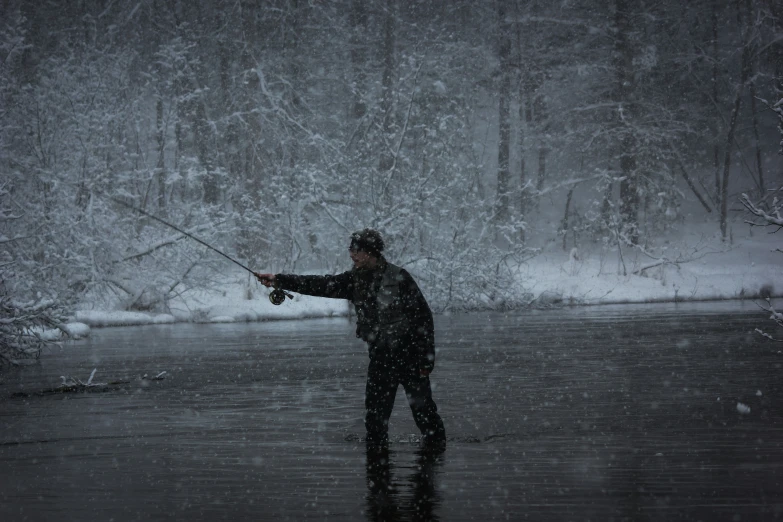 a man fishing in the water on a cold day