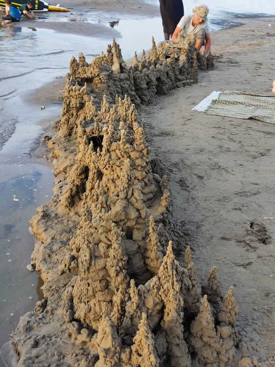 a sandy shore with two people and sandcastles