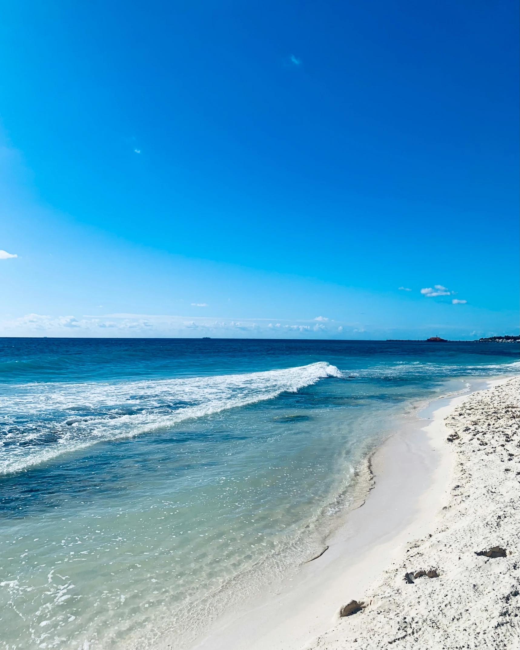 a beach area with several people walking on the sand