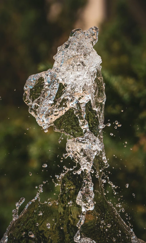 an open water fountain spewing on a large rock