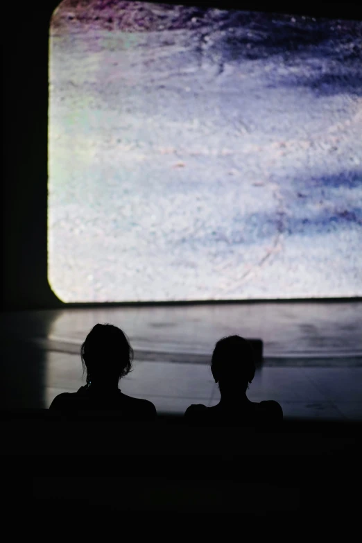 two people sitting in front of a big screen