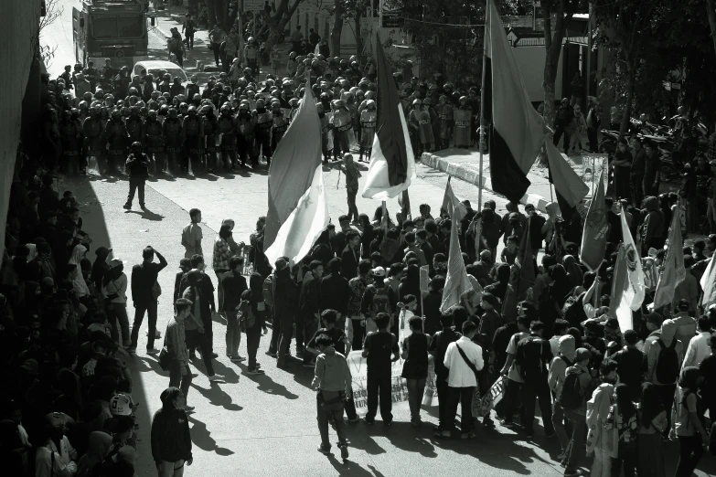 people are gathered in a courtyard, some with flags