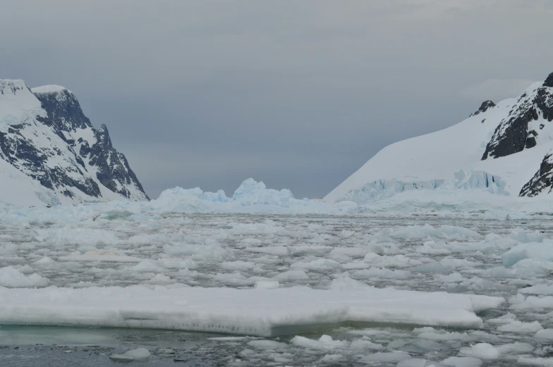 a couple of tall snow covered mountains in the middle of the ocean