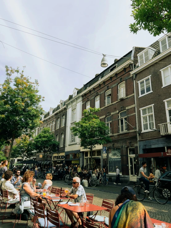 many people sitting at tables on a city sidewalk