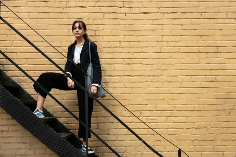 a woman with an orange purse is leaning against the wall