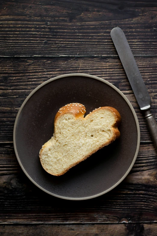 a slice of bread is on a plate next to a knife