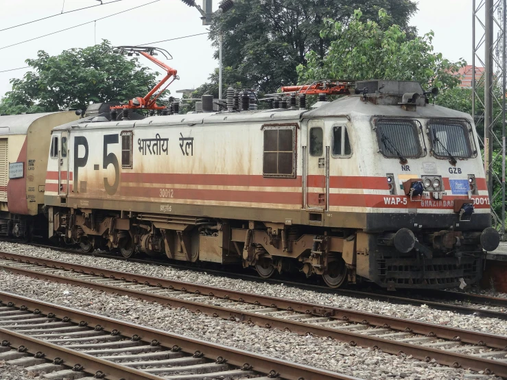 an old train sitting on the tracks by some trees