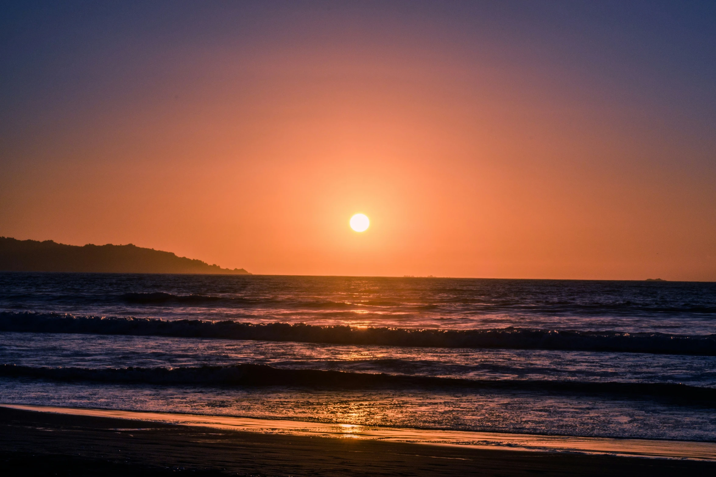 the sun rising over a small island with ocean waves