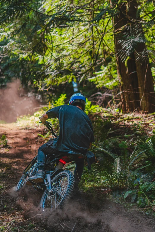 man on dirt bike kicking up dirt in forest