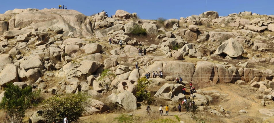 a rocky mountain side has a small group of people climbing it