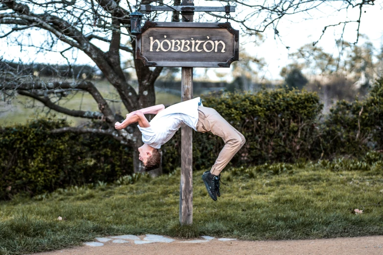 a man upside down hanging from a sign post