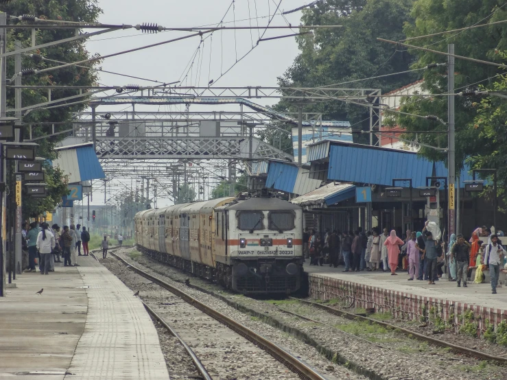 a train is pulling up to the station, as people wait to board