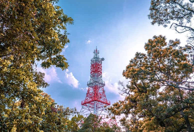 a tall red and silver tower towering over trees