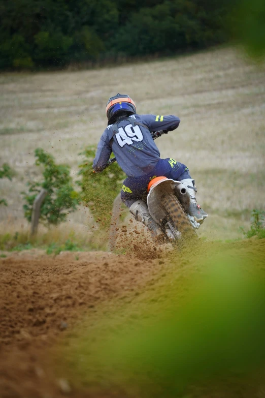 a man in blue is riding a dirt bike on a trail