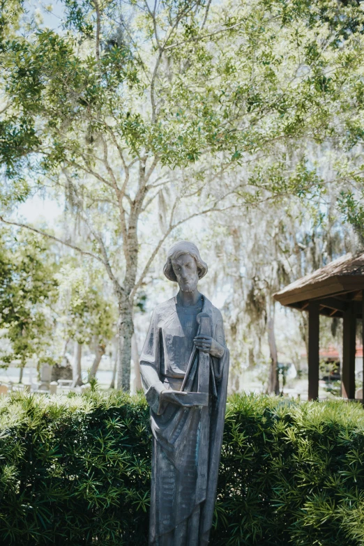 a statue is next to a shrub in the park