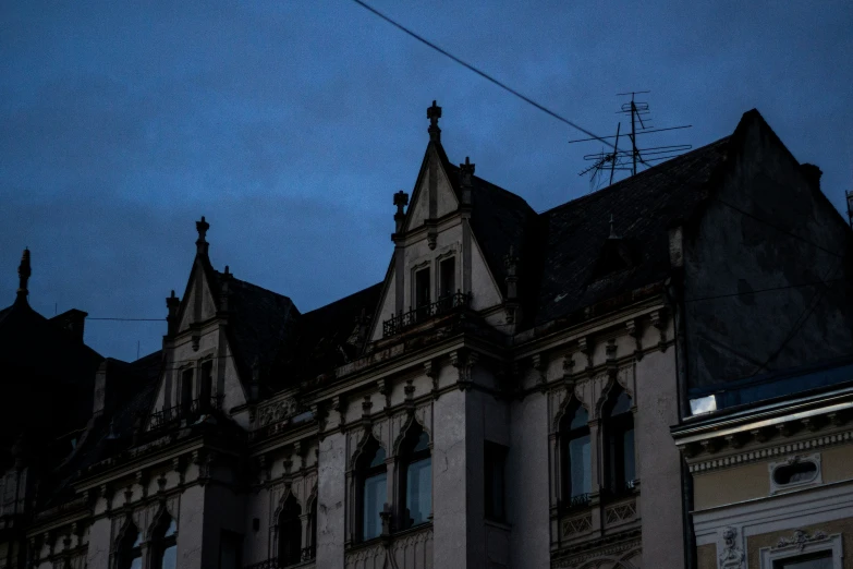 the front of a large building with many windows and dormies at night