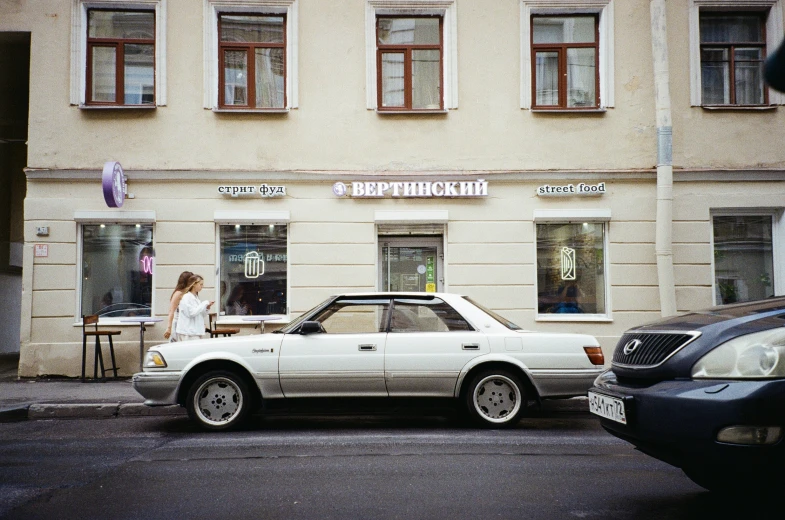 the white car parked next to the woman near a building