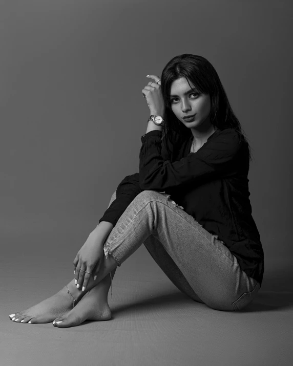 a young woman sitting in front of a black and white background