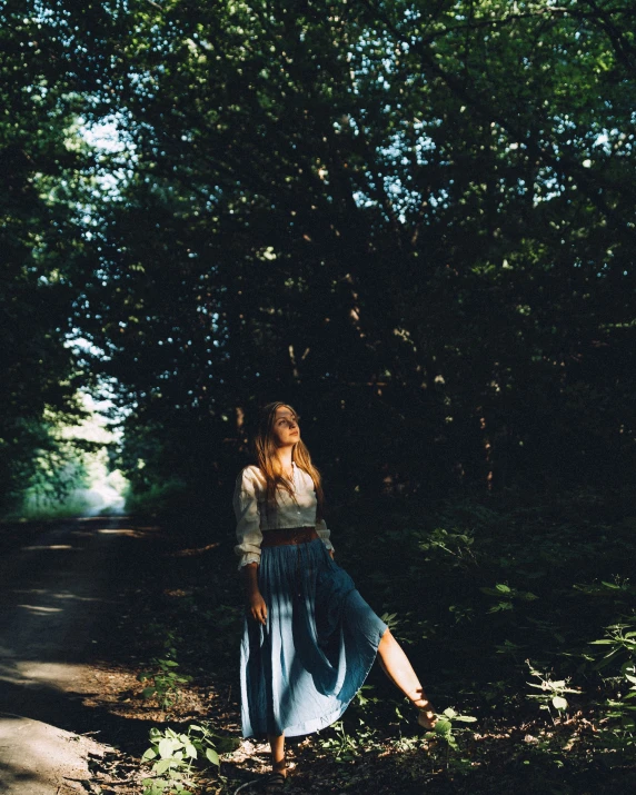 woman in long blue skirt walking in a park area