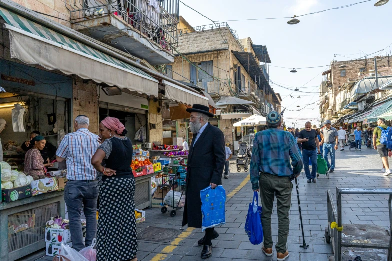 pedestrians walk down a narrow street lined with shops