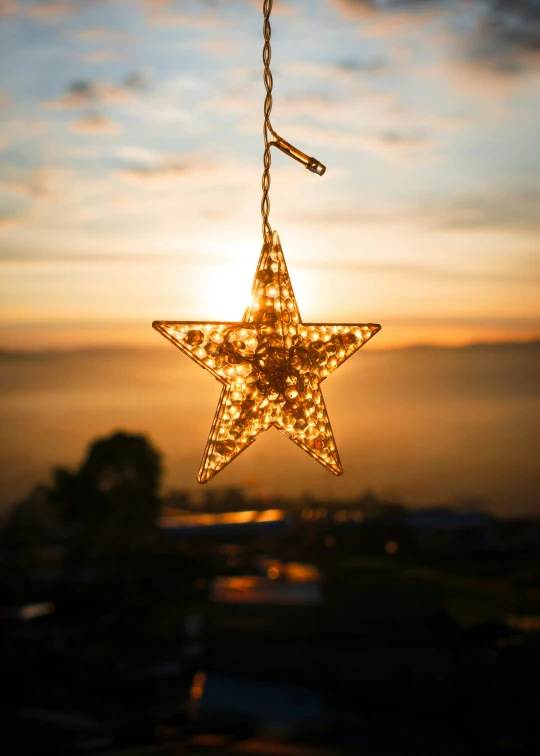 a christmas star hanging from a tree with lights inside it