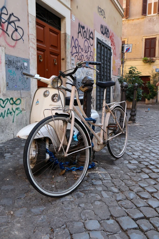 an old bike is parked in front of a wall with graffiti