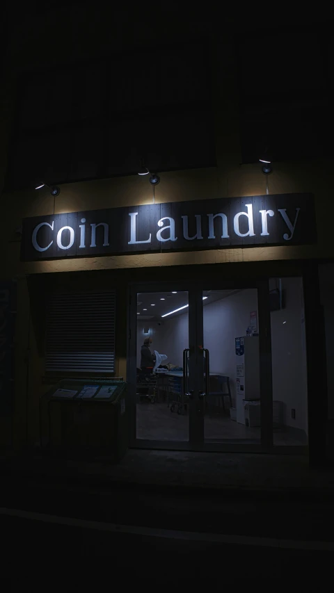 a dark room with a neon sign reading coin laundry