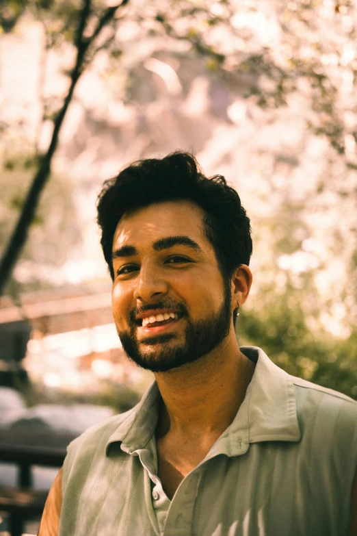 a man smiles to the camera in front of trees